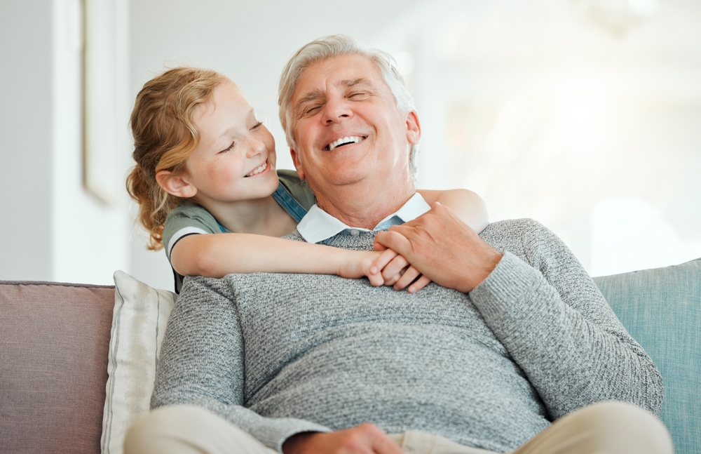 Smiling grandfather hugged by his granddaughter